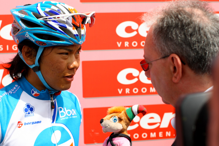 大会委員長のアンジェロ・ゾメニャン氏にマスコットを渡される新城幸也(日本、Bboxブイグテレコム)