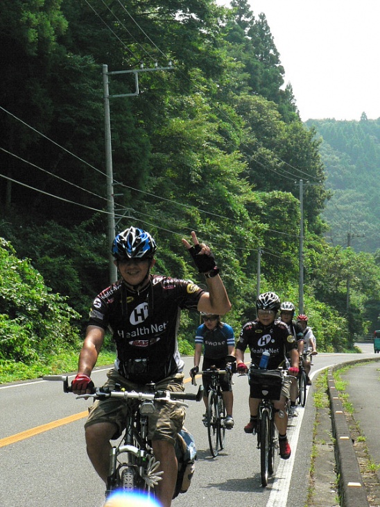 サイクリングを楽しむ参加者の皆さん。思わずピースも出る爽やかな光景の中を進んでいく