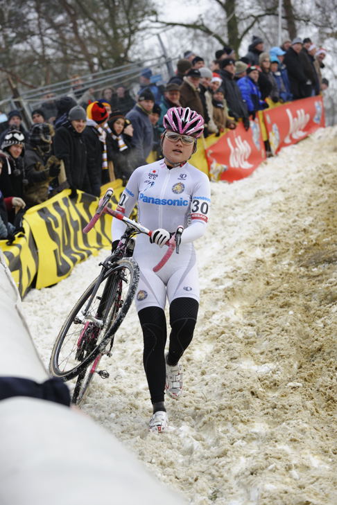 雪に覆われた下りでバイクを担ぐ豊岡英子(パナソニックレディース)