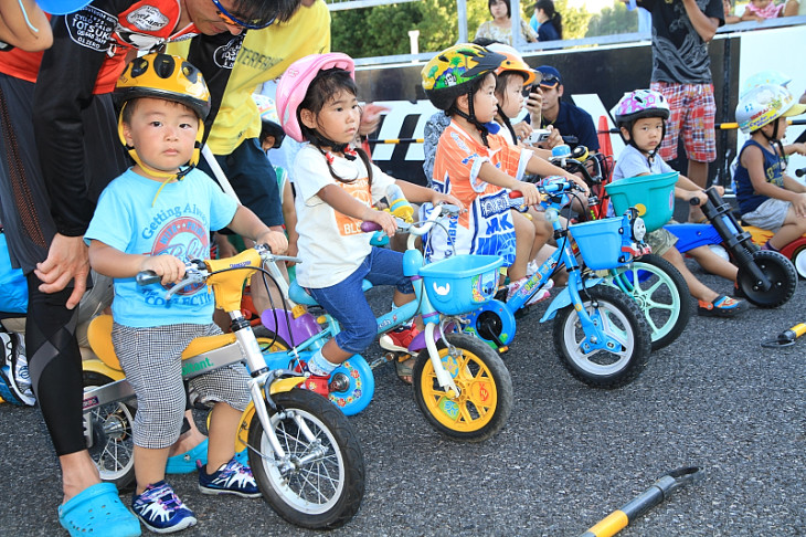 補助輪つき自転車で走るキッズたち。サポートする親のほうが熱心です