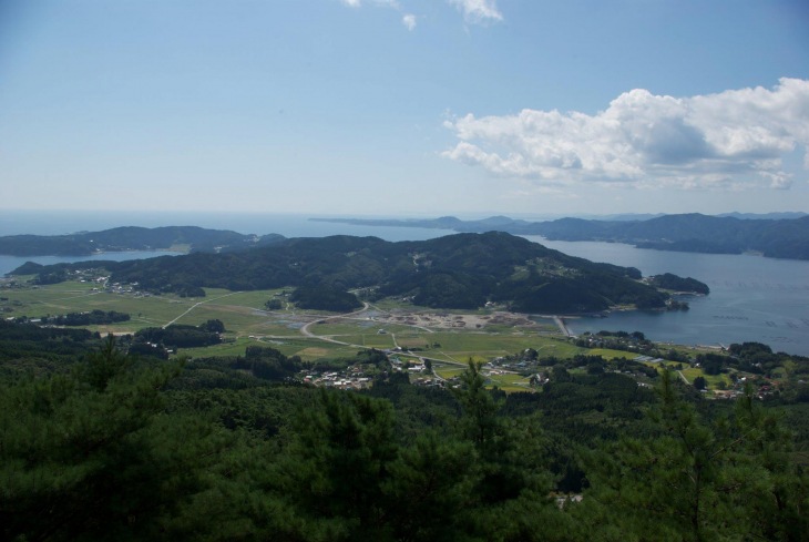 震災前の陸前高田市小友町の風景　緑の田畑が広がり、地元経済を支える牡蠣養殖の筏が見える