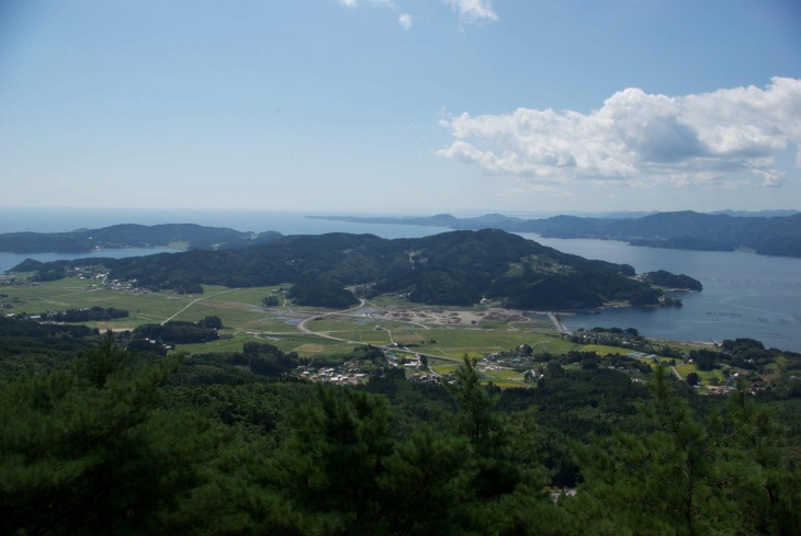 震災前の陸前高田市小友町の風景 緑の田畑が広がり、地元経済を支える牡蠣養殖の筏が見える