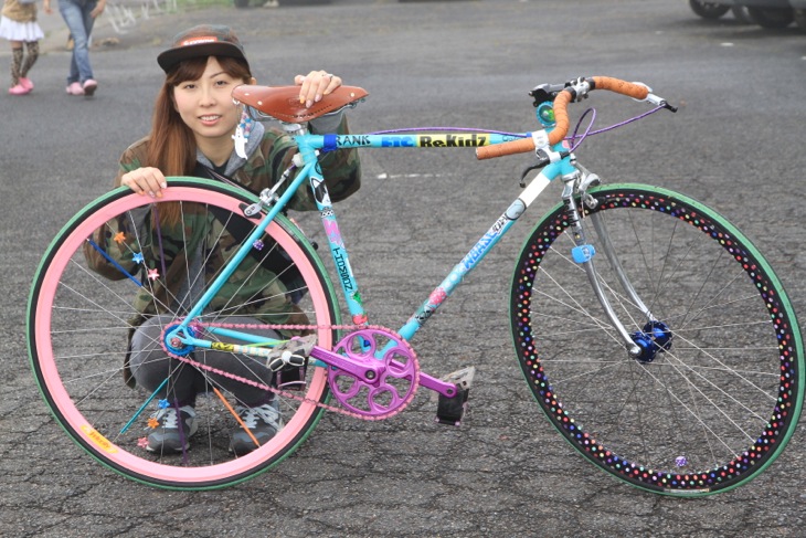 カラフルなデコが光るロードバイクに乗るAKKさん