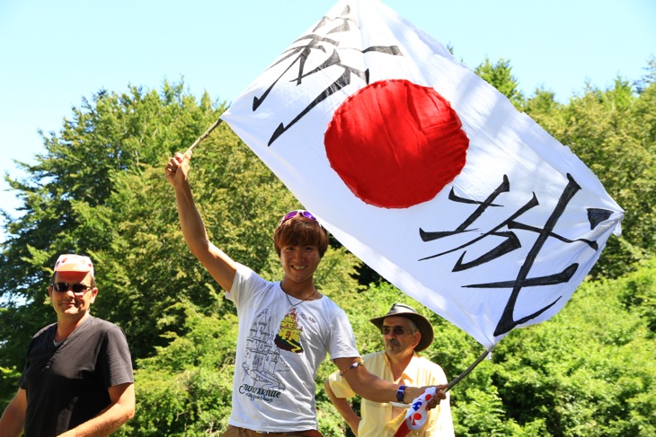 新城と大書きした日の丸の旗を振る日本からの観客