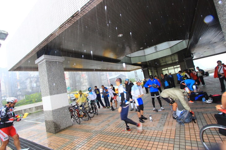 土砂降りの雨の降る中、駅のホームで用意を進める