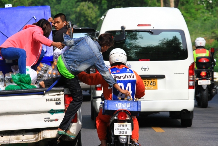 トラックの荷台から水のペットボトルをオートバイマーシャルに補給し、それが参加者に届けられる