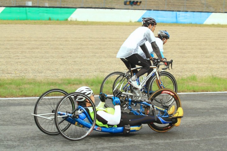 ロードレーサーの横をハンドサイクルが行く。他のイベントでは見かけられない光景だ