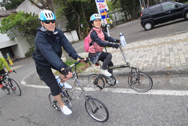 小径車で走るカップル。お揃いのヘルメットで決めています