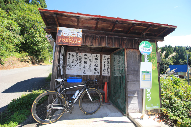 なんだか古びた看板が並んだ味のあるバス停で一休み？