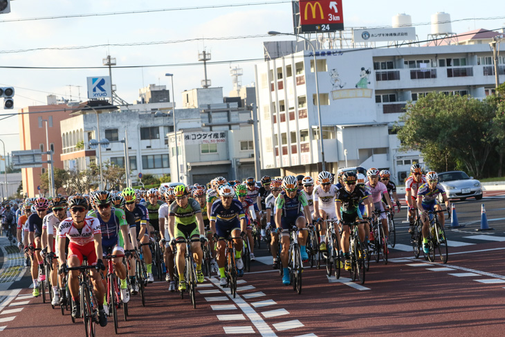 朝陽を背に浴びながら名護市街を走り出していく市民210kmの選手たち