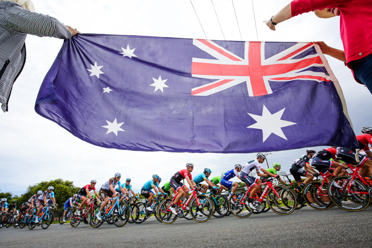 オーストラリア国旗を横目にプロトンは進む