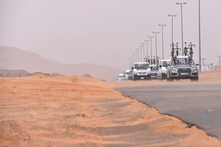砂嵐の中を移動するチームカーの車列