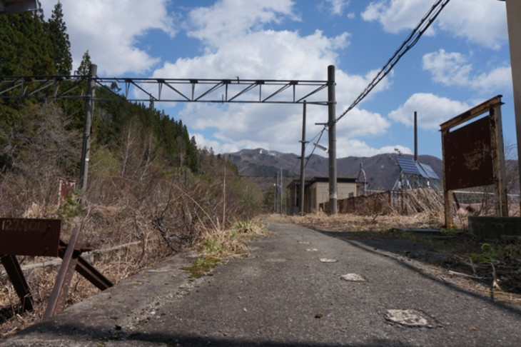 路盤には木が伸びて時の流れを感じさせますが、架線柱も駅名標もそのまま残っている旧ホーム