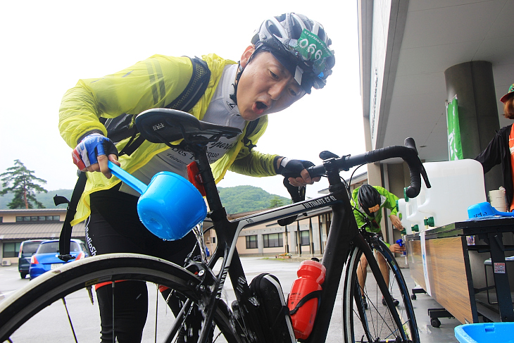 桶に用意された水で汚れた自転車を洗い流す