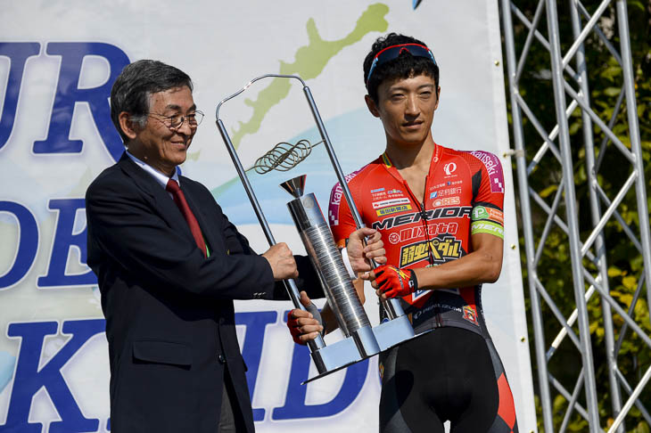 昨年個人総合優勝の増田成幸(宇都宮ブリッツェン)から、優勝トロフィーが返還される