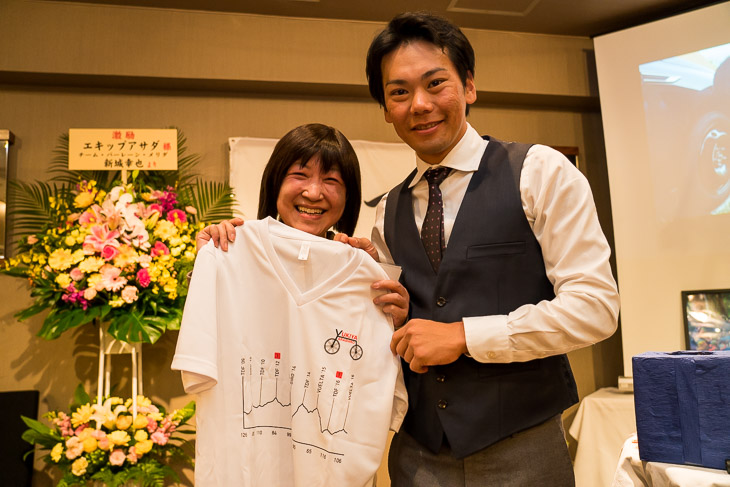 オリジナルTシャルをもらって笑顔のファン。新城幸也が完走したグランツール10回分をコースプロフィールに模したデザインとなっている