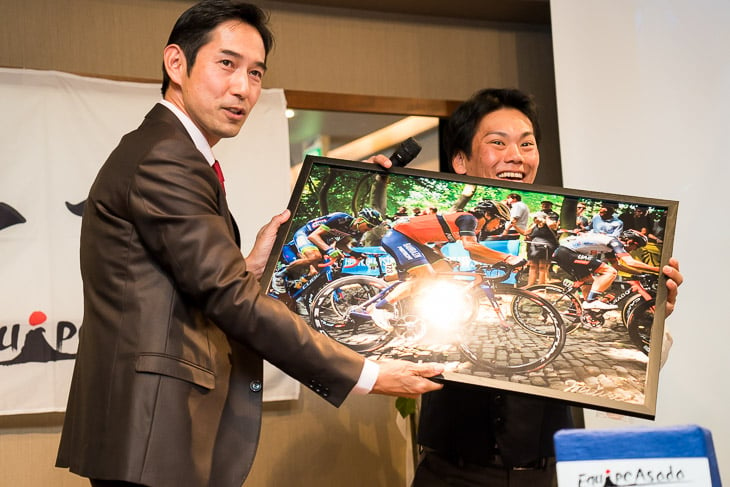 新城幸也の特大写真パネルが、まさにこのレースで新城を応援していたと言う浅田監督へ贈られた