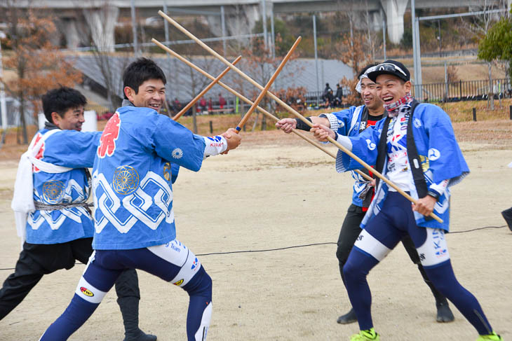 若干へっぴり腰で「棒の手」の手ほどきを受けるキナンサイクリングチームの阿曽圭佑選手と野中竜馬選手