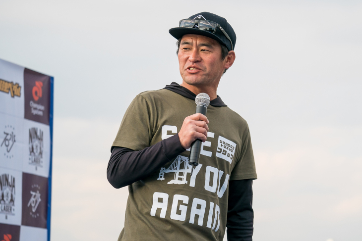 「SEE YOU AGAIN」とプリントされたスタッフTシャツを着て挨拶した棈木亮二代表