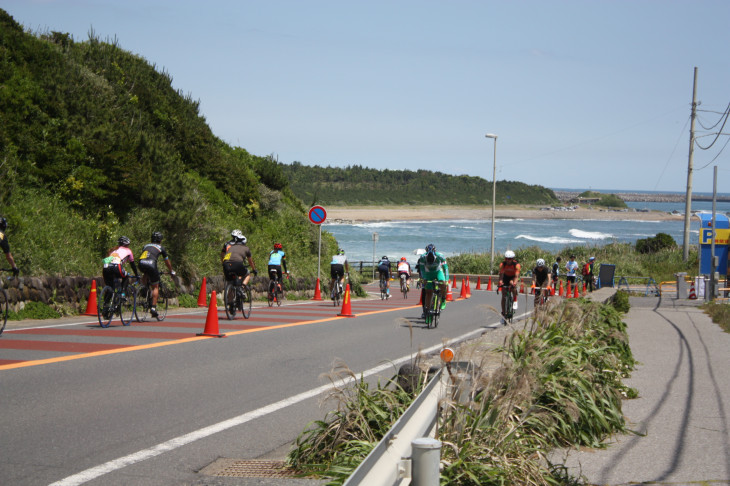 海をバックにサイクリストたちが走り抜ける