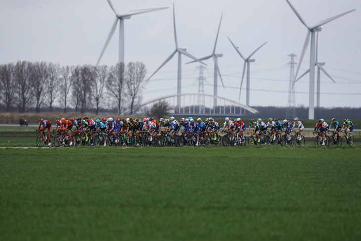 発電風車が回る平原を走る抜けるプロトン