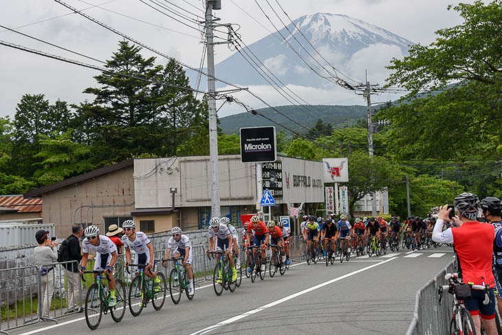 雲間から見える富士山をバックに集団が行く