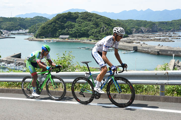 太地港を背景に登りを行くトマ・ルバ(キナンサイクリングチーム)と佐野淳哉(マトリックスパワータグ)
