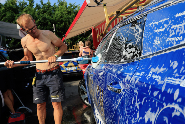 上裸でチームカーを洗車するスタッフ