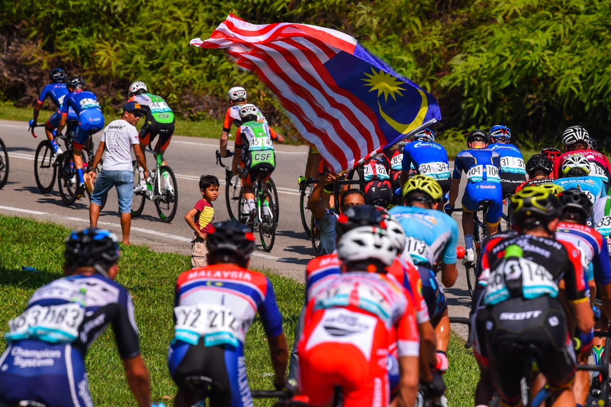 マレーシア国旗が翻る峠道を行くメイン集団