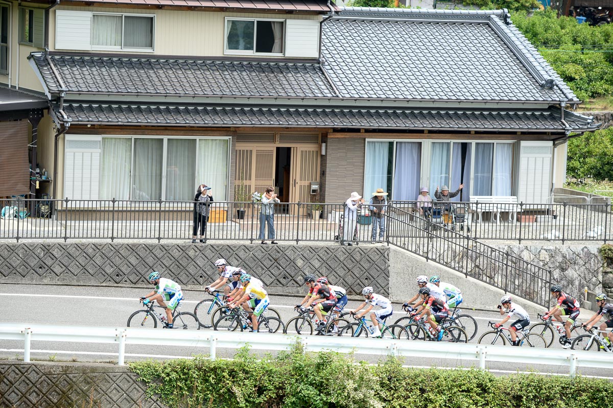 民家の庭先をレースが通り過ぎる