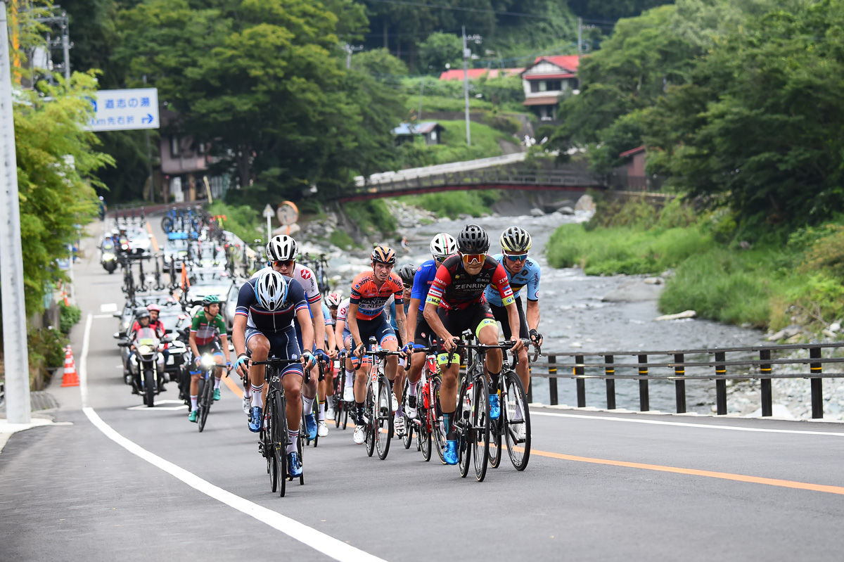 横塚浩平（チーム右京）を先頭に道志川沿いを行く19名の追走集団