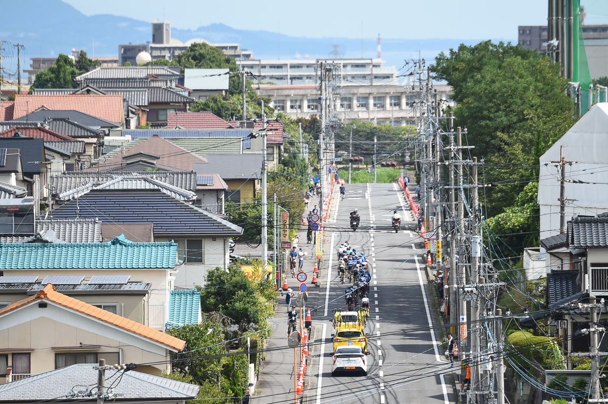 住宅街の中を行く集団。奥に別府湾が見える