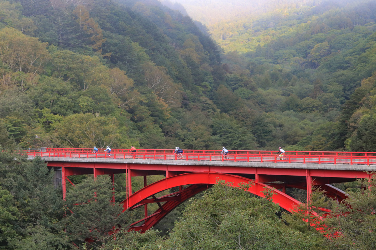 最高標高地点の赤い橋「東沢大橋」を渡る参加者たち