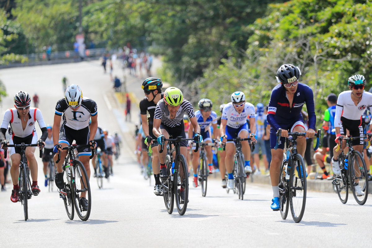 羽地ダムへの登りを走る市民100kmマスターズの選手たち