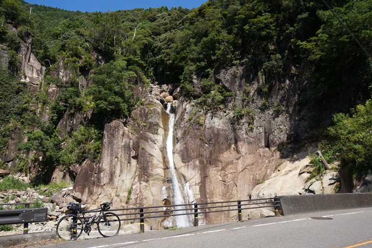 道路わきの岩壁から流れ落ちる滝に涼を求めるが暑すぎておかしくなりそう！！