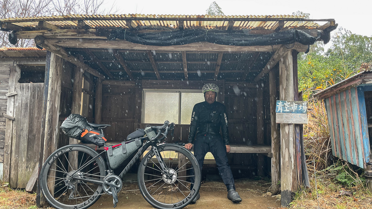 屋根を見つけて雨宿り。「青空市場」とあるのは皮肉かな?