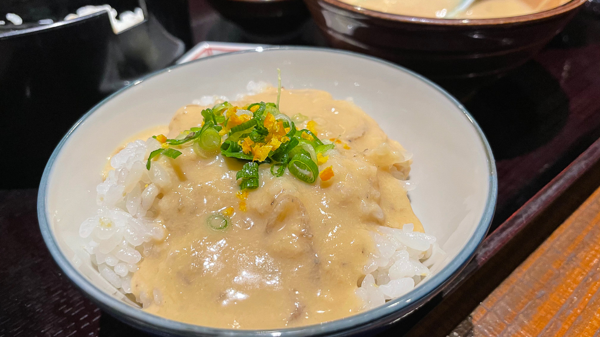 麦味噌の汁を麦飯にかけてネギ、みかんの皮の薬味とともに食べる