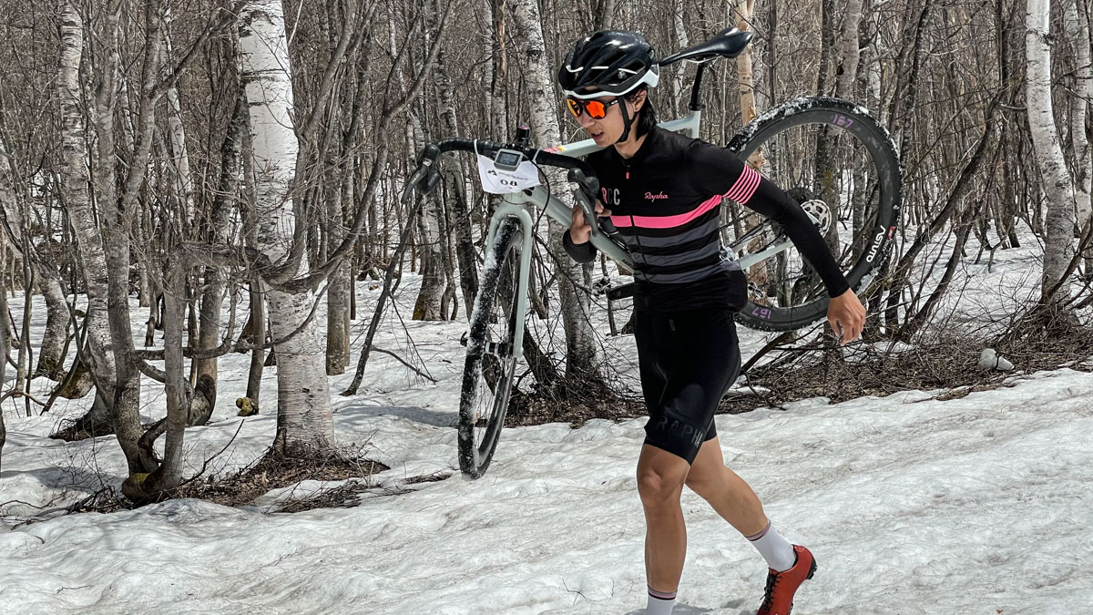 バイクを担いで雪原を行くトップの吉川大地選手（Rapha Cycle Club）