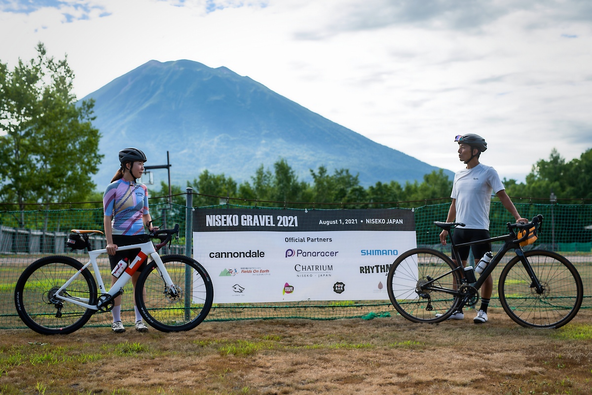 スタート前に山本和弘さん（キャノンデール・ジャパン）と談笑する佐藤さん。背後にはニセコ地区のシンボル、羊蹄山が見える