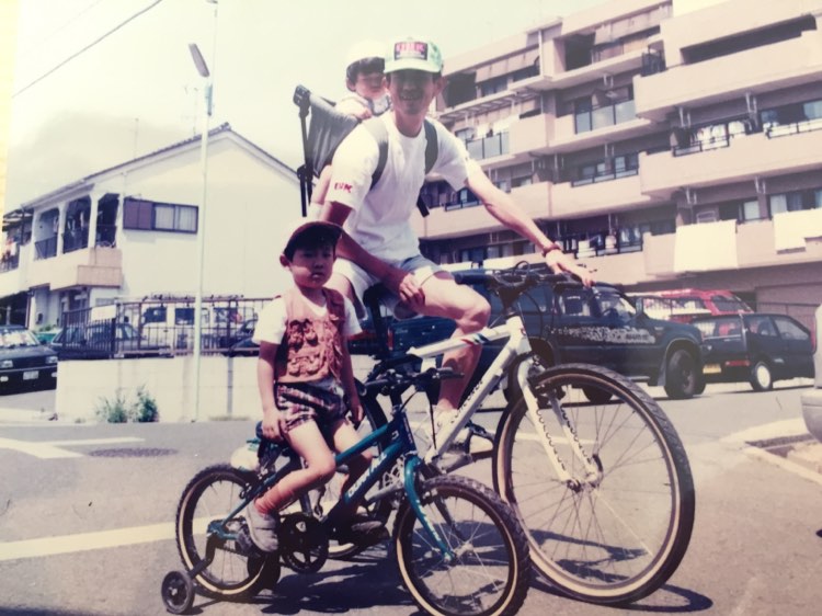 父親の中根賢二さんと自転車にまたがる