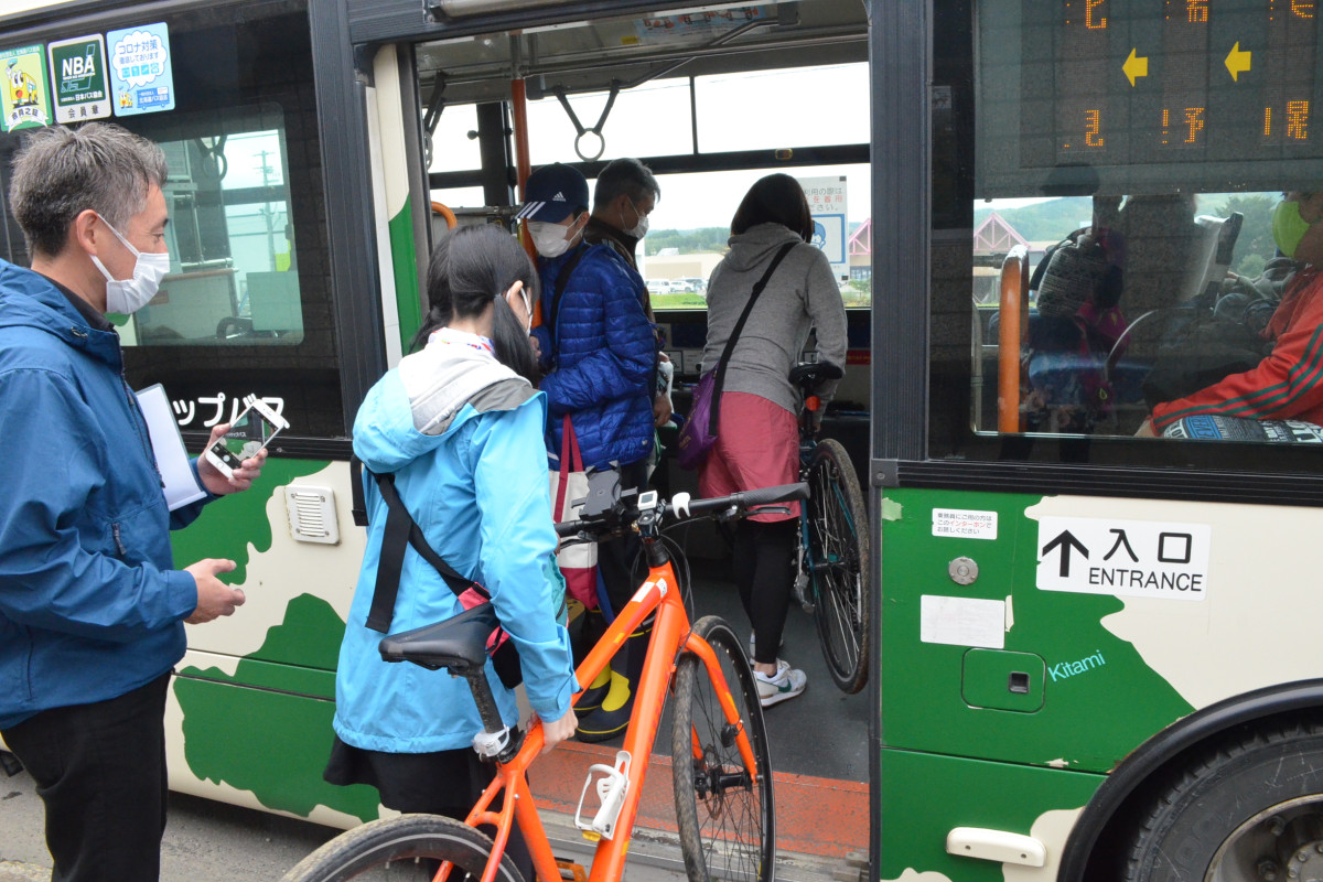 バスに自転車を積み込む2人