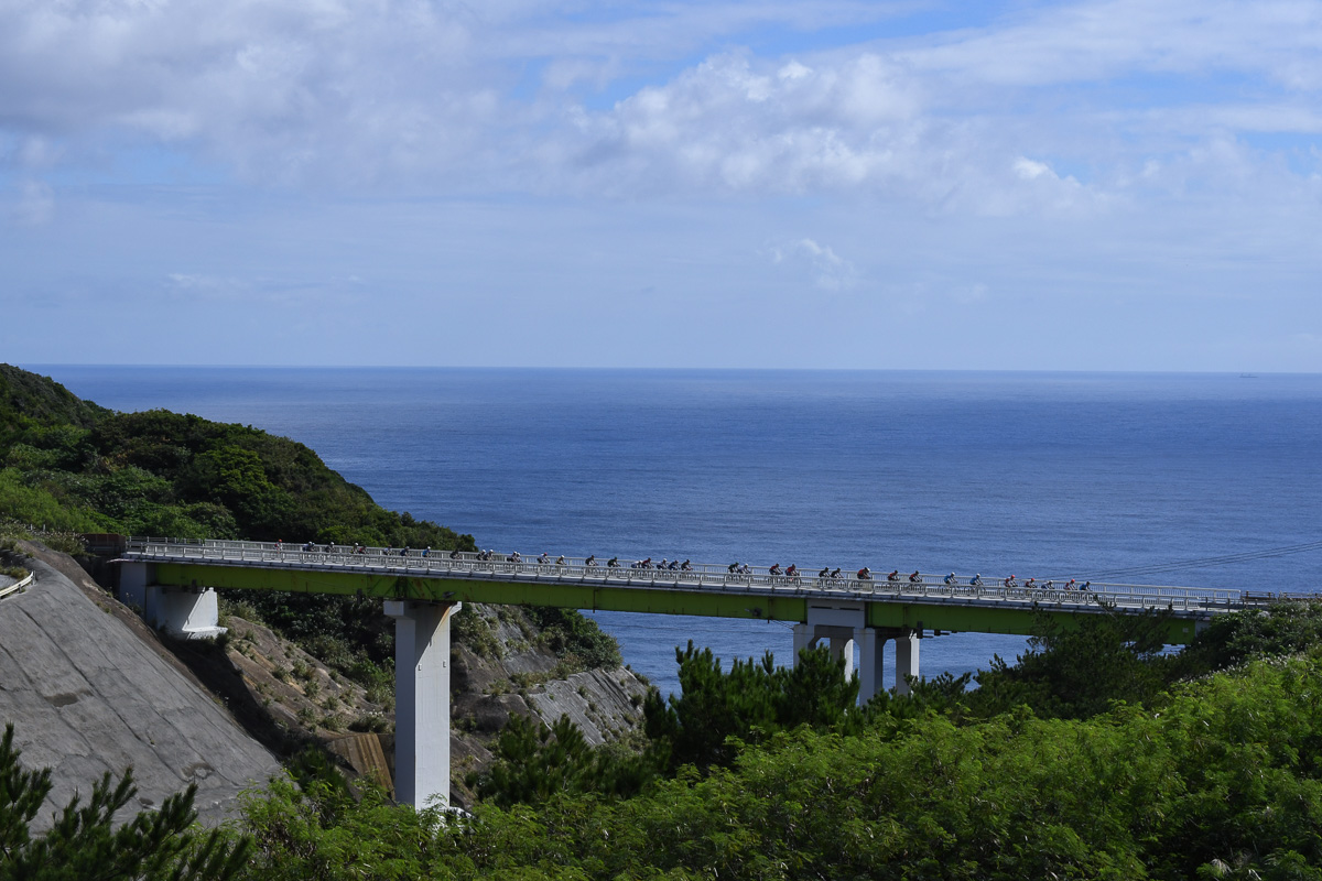 沖縄本島東側の海岸を行く集団　レース中盤以降は青空が広がった