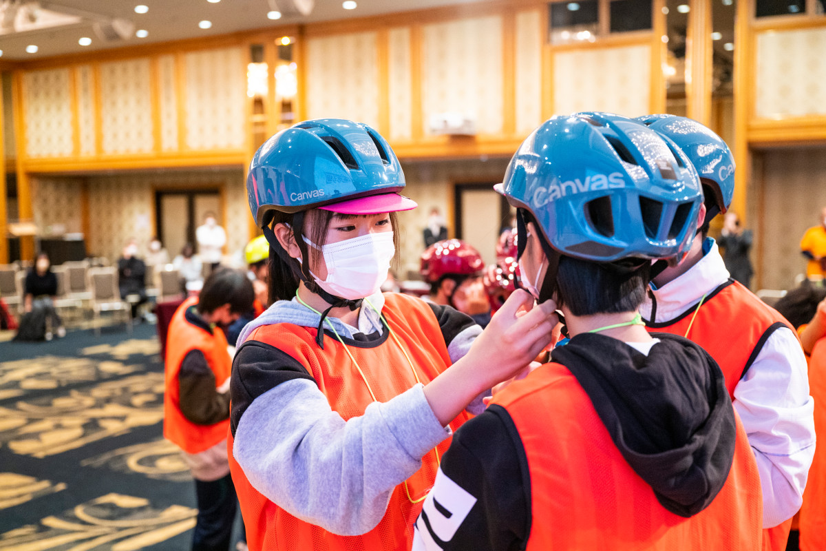 実技【ヘルメットの装着】で、お互いのヘルメットをチェックし合う生徒たち